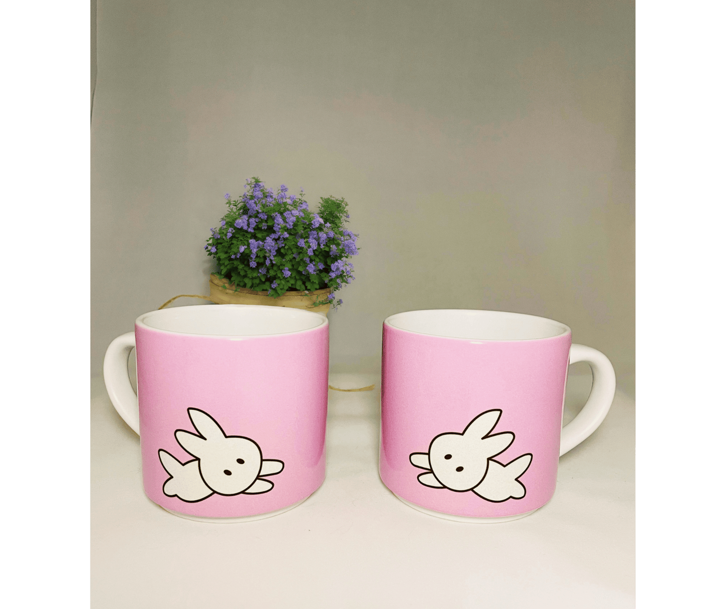 2 pink stackable 10 oz mugs in front of a white background with a plant